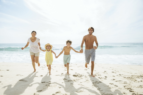 Familie läuft gemeinsam am Strand, lizenzfreies Stockfoto