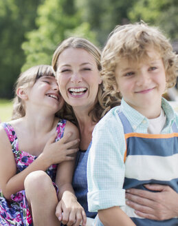 Mutter und Kinder lächeln im Freien - CAIF18098