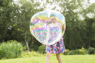 Father and daughter playing with large bubbles in backyard - CAIF18105