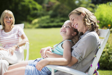 Mother and daughter relaxing in backyard - CAIF18108