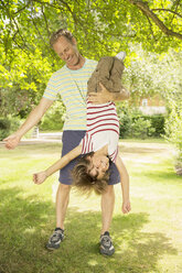 Father holding son upside-down in backyard - CAIF18120