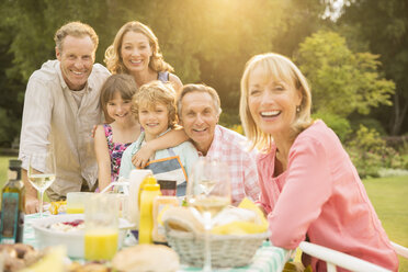 Mehrgenerationenfamilie am Tisch im Hinterhof - CAIF18130