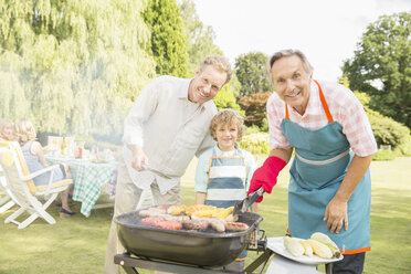Mehrgenerationen-Männer grillen Fleisch und Mais auf einem Grill im Hinterhof - CAIF18133