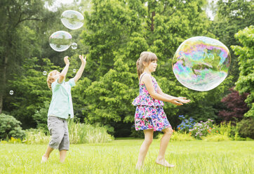 Kinder spielen mit Seifenblasen im Freien - CAIF18135