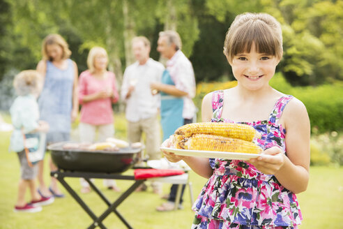 Lächelndes Mädchen mit gegrilltem Mais im Hinterhof - CAIF18136