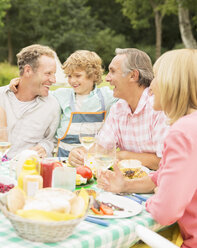 Familie genießt das Mittagessen am Tisch im Hinterhof - CAIF18140