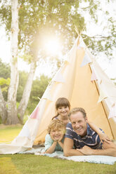 Vater und Kinder entspannen sich im Tipi im Hinterhof - CAIF18142