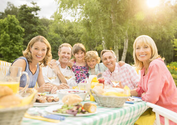 Multi-generation family enjoying lunch at table in backyard - CAIF18143