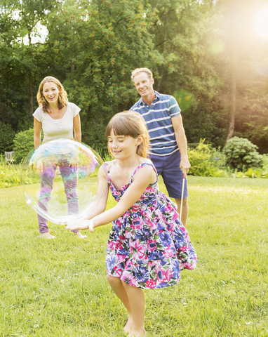 Familie spielt mit Seifenblasen im Hinterhof, lizenzfreies Stockfoto