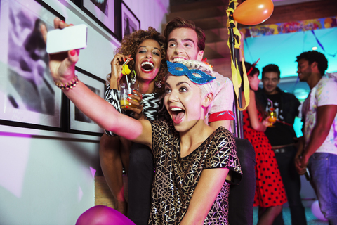 Freunde machen Selbstporträts mit der Handykamera auf einer Party, lizenzfreies Stockfoto