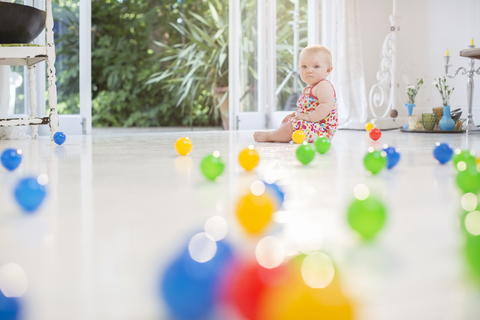 Babymädchen mit Spielzeug auf dem Küchenboden, lizenzfreies Stockfoto