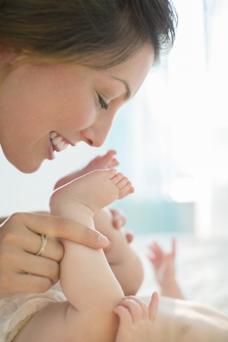 Mutter küsst die Füße eines kleinen Mädchens, lizenzfreies Stockfoto