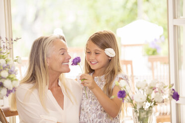 Grandmother and granddaughter smelling flowers - CAIF18248