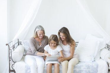 Multi-generation women using digital tablet on daybed - CAIF18249