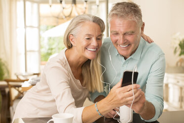 Älteres Paar teilt sich einen mp3-Player in der heimischen Küche - CAIF18255
