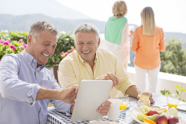 Ältere Männer benutzen ein digitales Tablet am Terrassentisch - CAIF18276