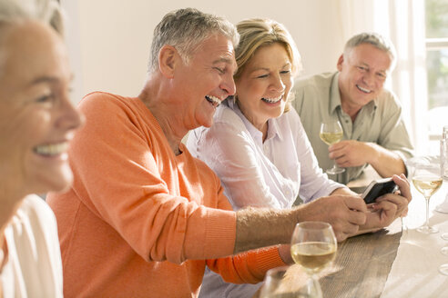 Ältere Paare trinken Wein und schauen auf ihr Handy - CAIF18278