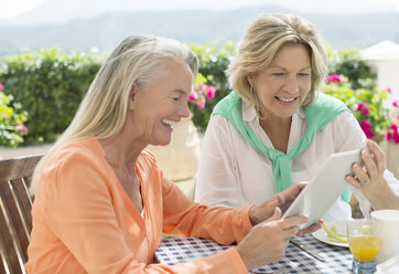 Ältere Frauen benutzen ein digitales Tablet am Terrassentisch - CAIF18279