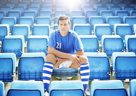 Fußballspieler sitzt im leeren Stadion - CAIF18328