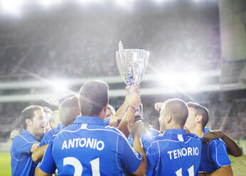 Soccer team celebrating with trophy on field - CAIF18335