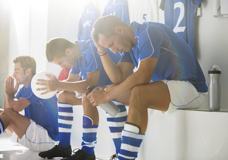 Enttäuschte Fußballspieler sitzen in der Umkleidekabine - CAIF18337