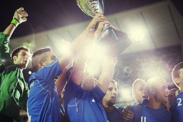 Soccer team celebrating with trophy on field - CAIF18339