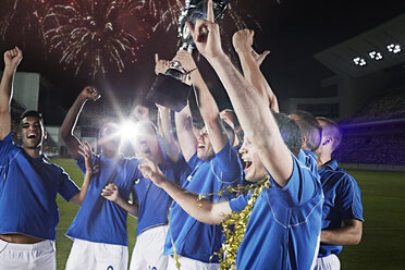 Soccer team cheering with trophy on field - CAIF18347