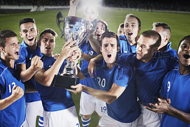 Soccer team cheering with trophy on field - CAIF18354