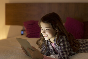 Mädchen mit digitalem Tablet auf dem Bett - CAIF18423