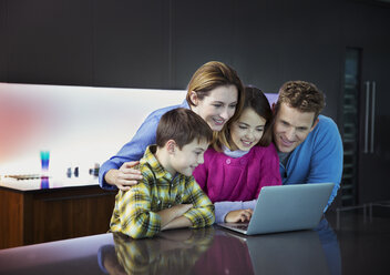 Familie benutzt Laptop gemeinsam in der Küche - CAIF18437