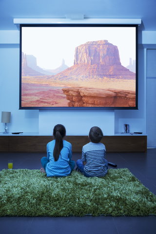 Kinder beim Fernsehen im Wohnzimmer, lizenzfreies Stockfoto
