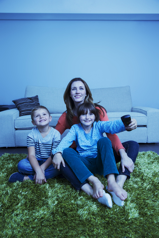 Mutter und Kinder beim Fernsehen im Wohnzimmer, lizenzfreies Stockfoto
