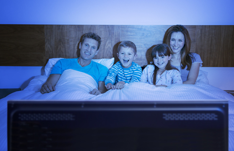 Familie beim Fernsehen im Bett, lizenzfreies Stockfoto