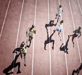 Relay runners handing off baton on track - CAIF18479