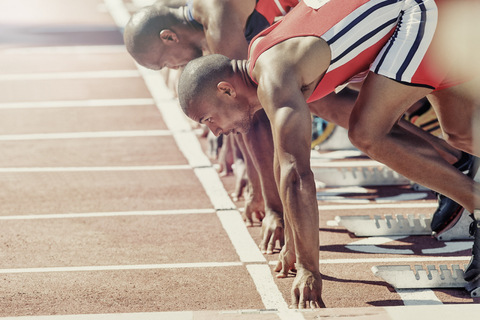 Die Läufer stehen am Startblock bereit, lizenzfreies Stockfoto