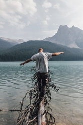 Kanada, Britisch-Kolumbien, Yoho-Nationalpark, Mann balanciert auf Baumstamm am Emerald Lake - GUSF00564