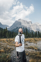 Canada, British Columbia, Yoho National Park, man holding selfie stick - GUSF00565