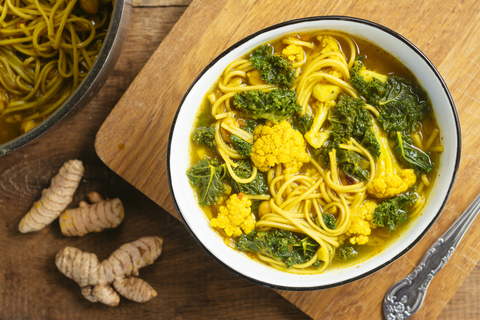 Turmeric broth, detox soup with soba noodles, kale, cauliflower and chickpeas stock photo