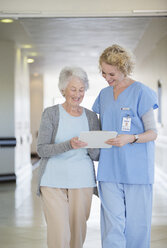 Krankenschwester und alternder Patient beim Lesen der Krankenakte im Krankenhausflur - CAIF18501