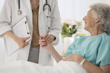 Arzt und alternder Patient halten Hände im Krankenhaus - CAIF18502