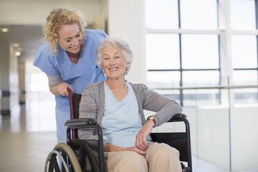 Nurse and aging patient smiling in hospital corridor - CAIF18504