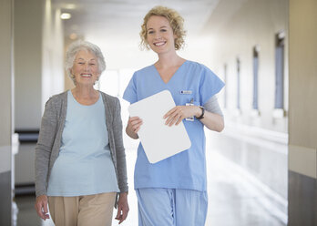 Porträt einer lächelnden Krankenschwester und eines älteren Patienten im Krankenhausflur - CAIF18506