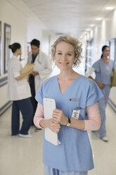 Porträt einer lächelnden Krankenschwester im Krankenhauskorridor - CAIF18507