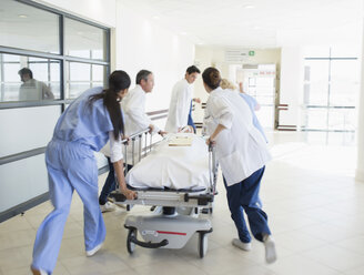 Ärzte hetzen einen Patienten auf einer Bahre den Krankenhausflur hinunter - CAIF18512