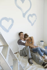 Couple painting blue hearts on wall - CAIF18542