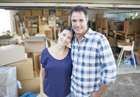 Porträt eines lächelnden Paares vor der Garage zwischen Kartons - CAIF18577