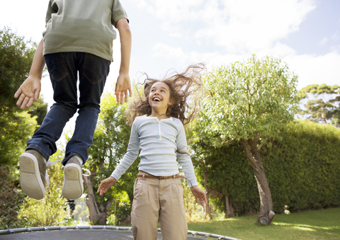 Kinder springen auf dem Trampolin im Hinterhof, lizenzfreies Stockfoto