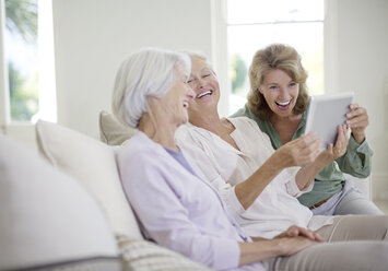 Ältere Frauen nutzen ein digitales Tablet auf dem Sofa - CAIF18592