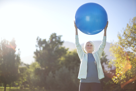 Ältere Frau hält Fitnessball im Park, lizenzfreies Stockfoto
