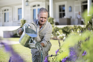 Älterer Mann bewässert Pflanzen im Garten - CAIF18596